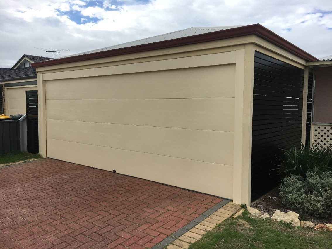 Cream garage door installation with dark brown fencing.