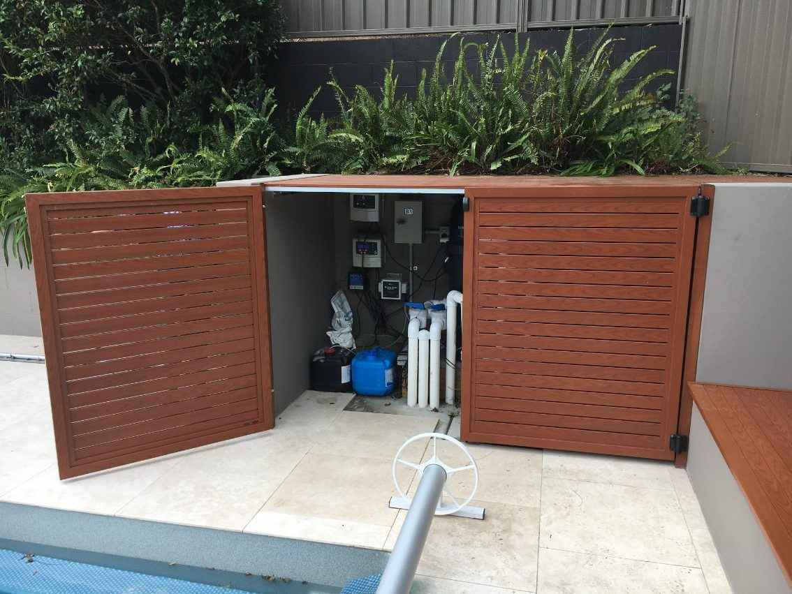 Light brown wooden pool box with pool cover roller installation next to swimming pool